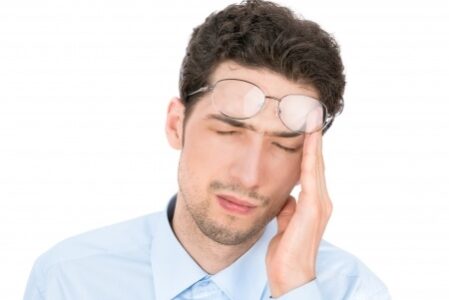 Man rubbing his heads pushing his glasses up onto his forehead