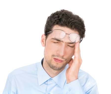 Man rubbing his heads pushing his glasses up onto his forehead