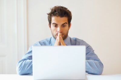 man looking at his computer hopeful