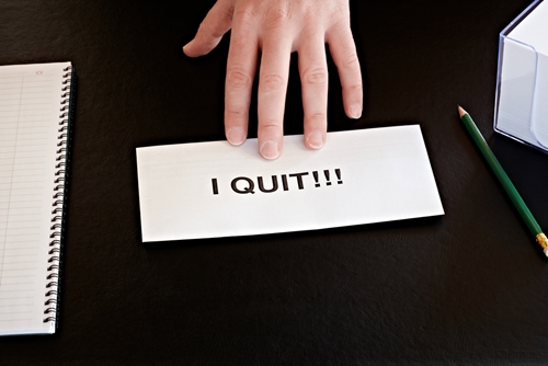 person pushing a piece of paper saying "I quit" on it