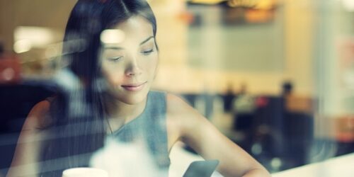 woman looking at her phone in a coffee shop