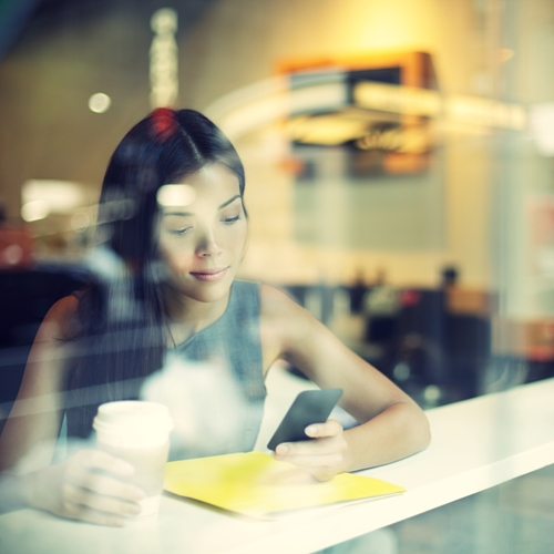 woman looking at her phone in a coffee shop