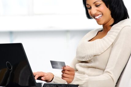 Woman on a laptop smiling at her credit card