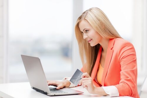 woman on her laptop in an office with a credit card in her hand