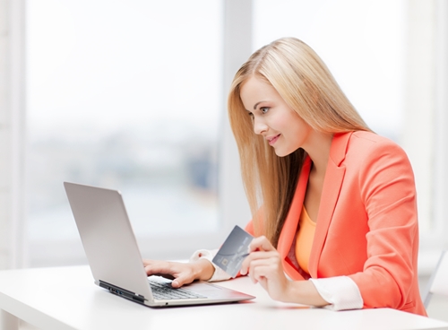 woman on her laptop in an office with a credit card in her hand