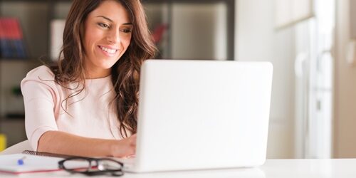 Woman smiling as she works on her laptop in a bright office