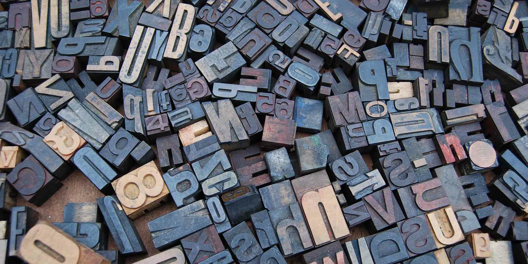 Wooden blocks with letters and numbers all laying in a jumble on the floor.